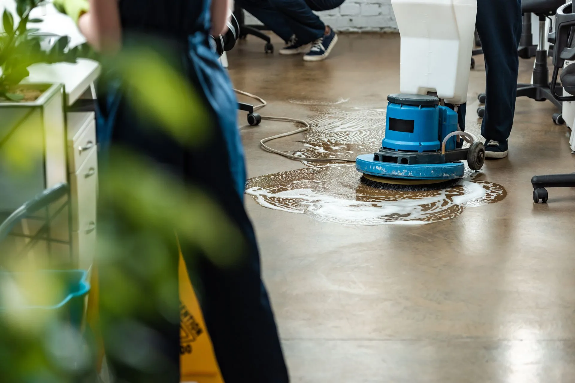 A person is cleaning a floor with a machine in an office. A person is cleaning a floor with a machine in an office.